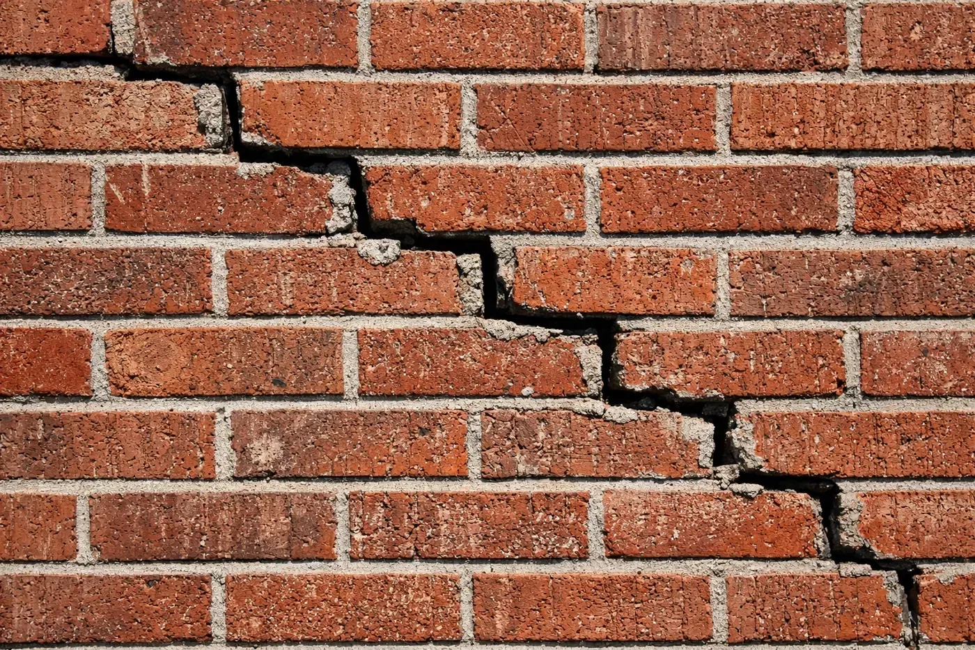 Stair-step cracks in a Dallas residential brick wall showing the need for professional masonry repair.
