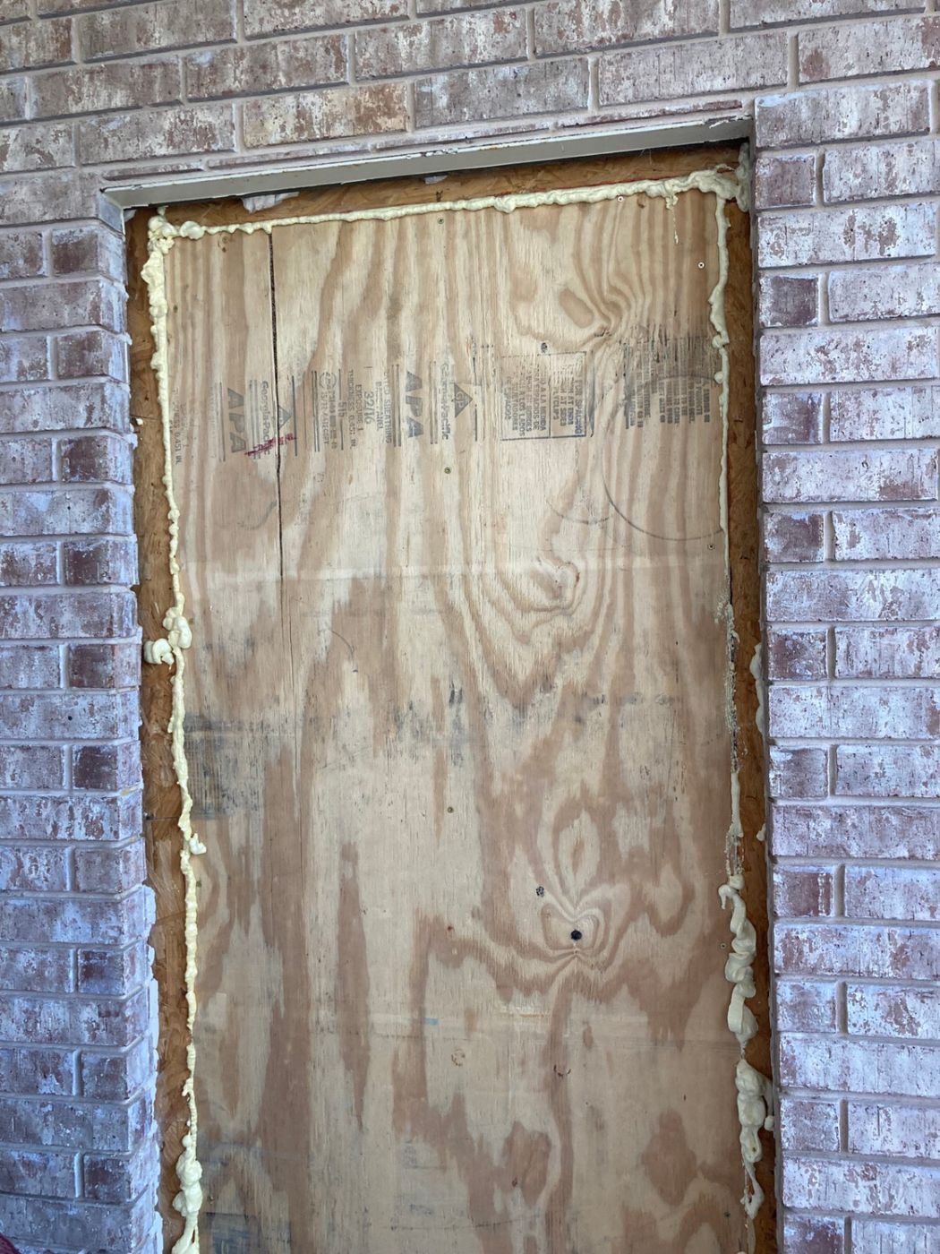 Temporary Plywood and Spray Foam Sealing in Brick Wall