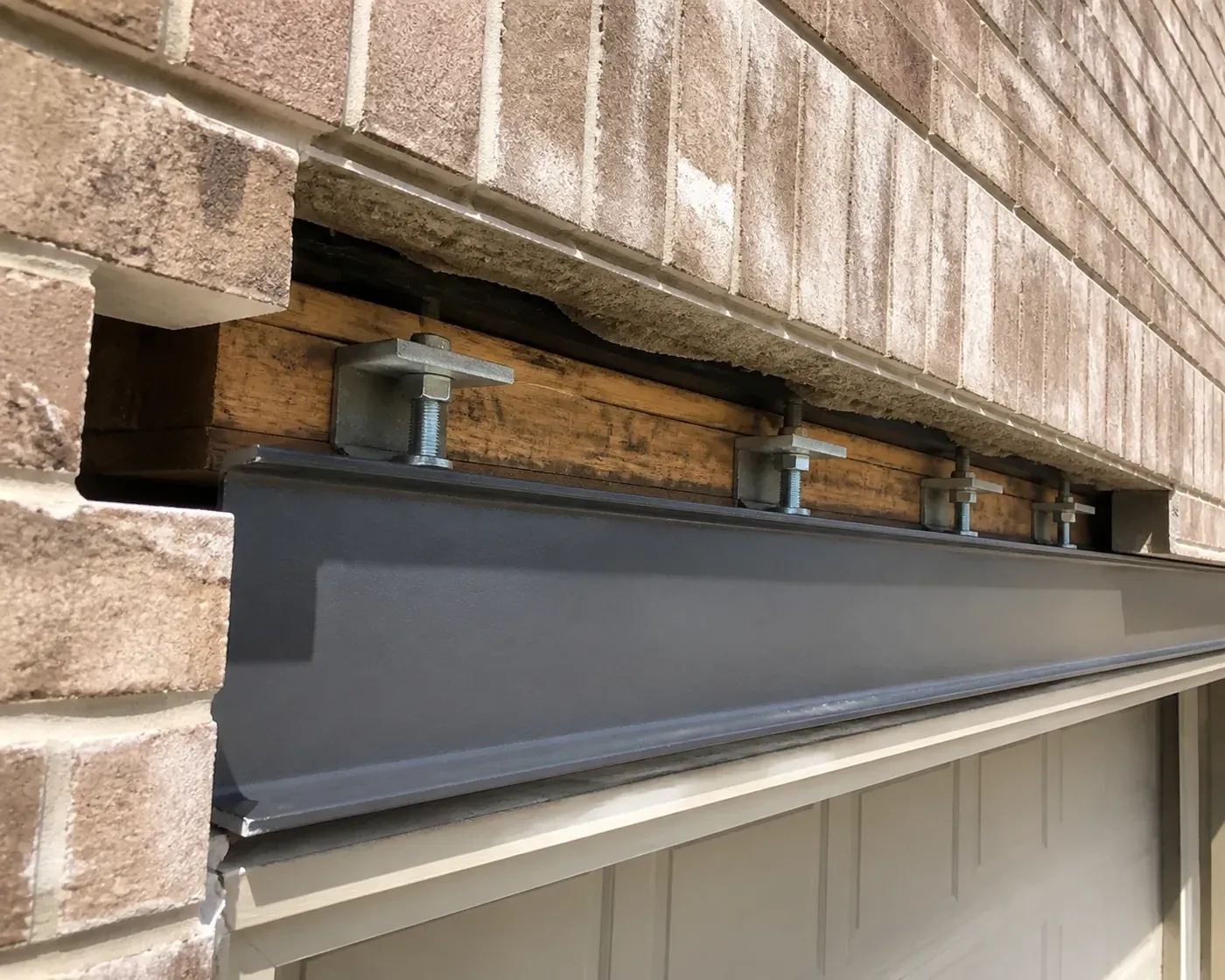 Installing LintleLOCK structural anchors to correct garage lintel rotation in a Dallas home.