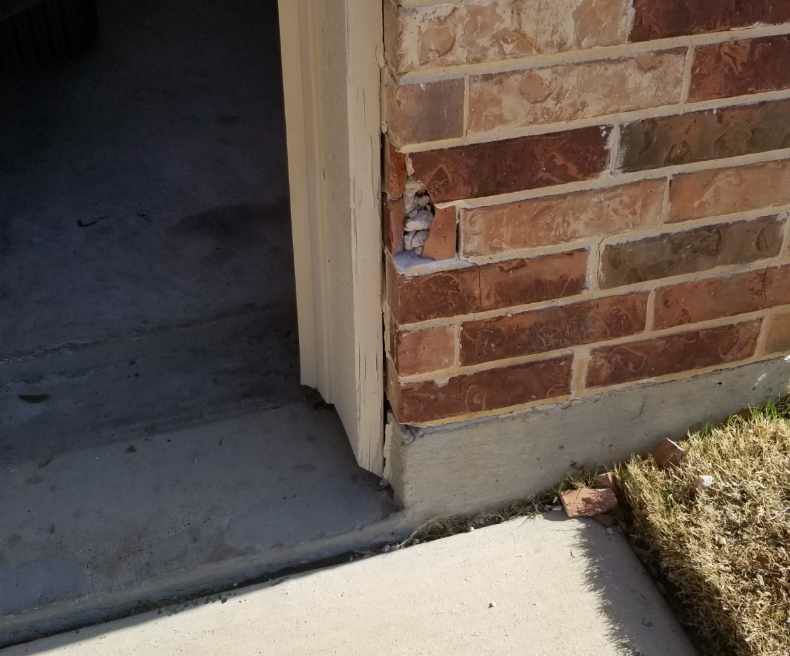 Close view of damaged brick and mortar at a garage-side wall, ready for careful replacement and blending