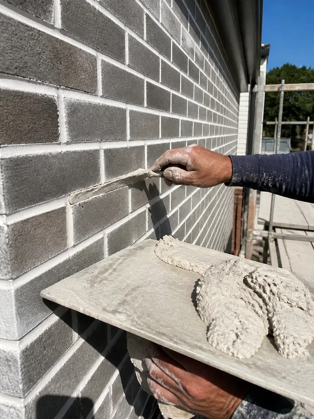 Expert mason applying mortar for new brick construction in Dallas TX on a professional job site.